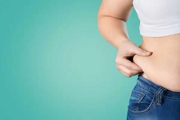Image of woman pinching her love handles to show weight gain Port Glasgow