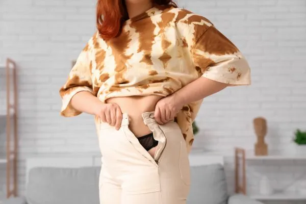 Image of woman trying to do her trousers up after pregnancy weight gain Port Glasgow