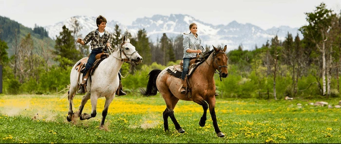 Confident plus-size woman riding Port Glasgow a horse through a field with a smile on her face.